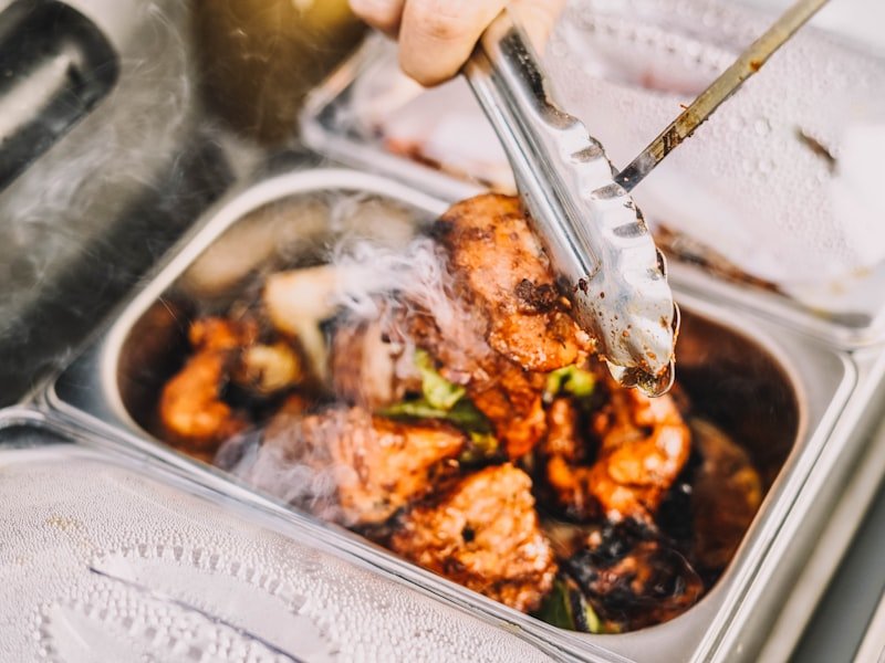 A plated dish being finished by hand, showing the care behind off-site catering